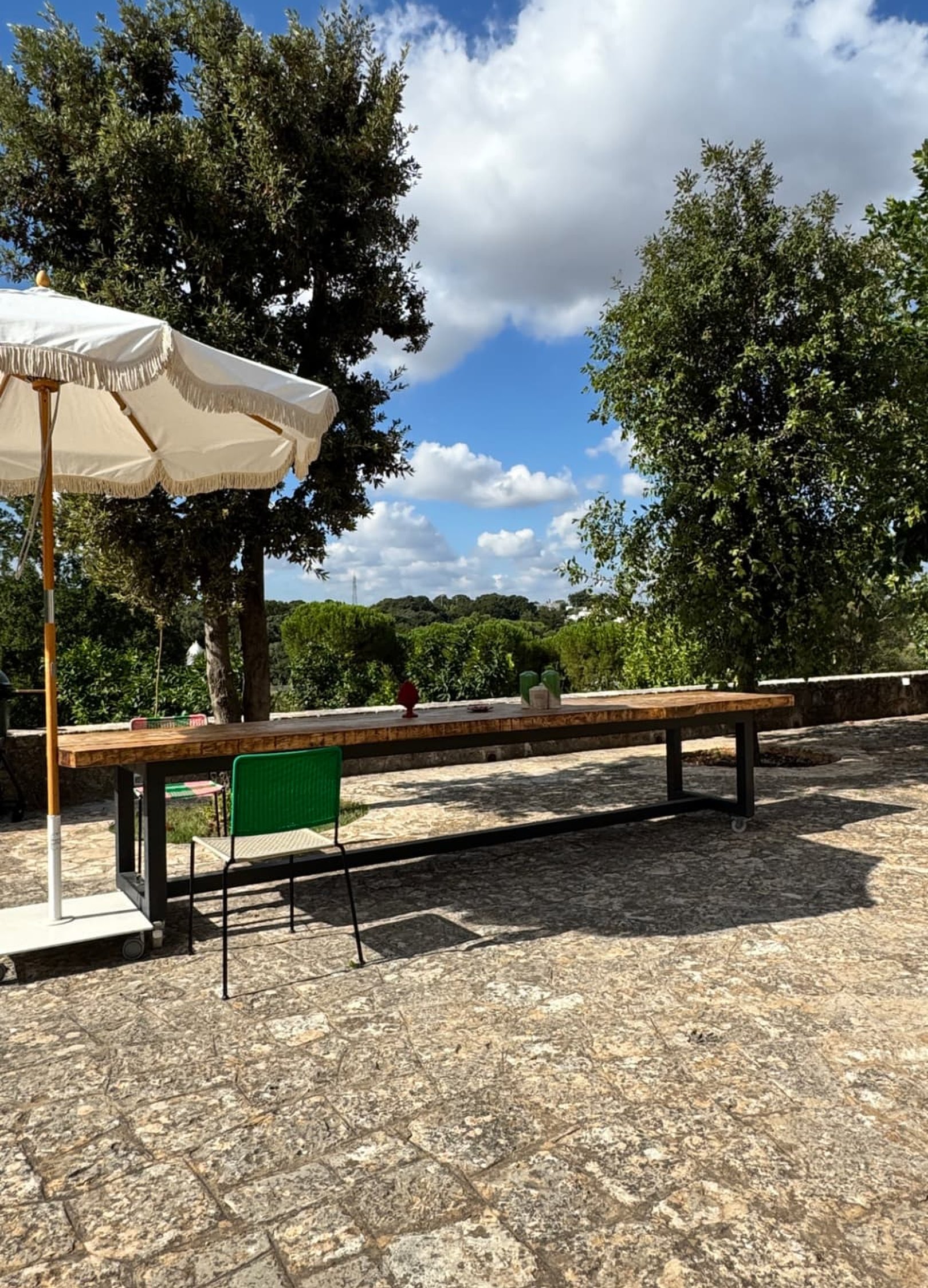 Long wooden table under a white parasol on a stone terrace