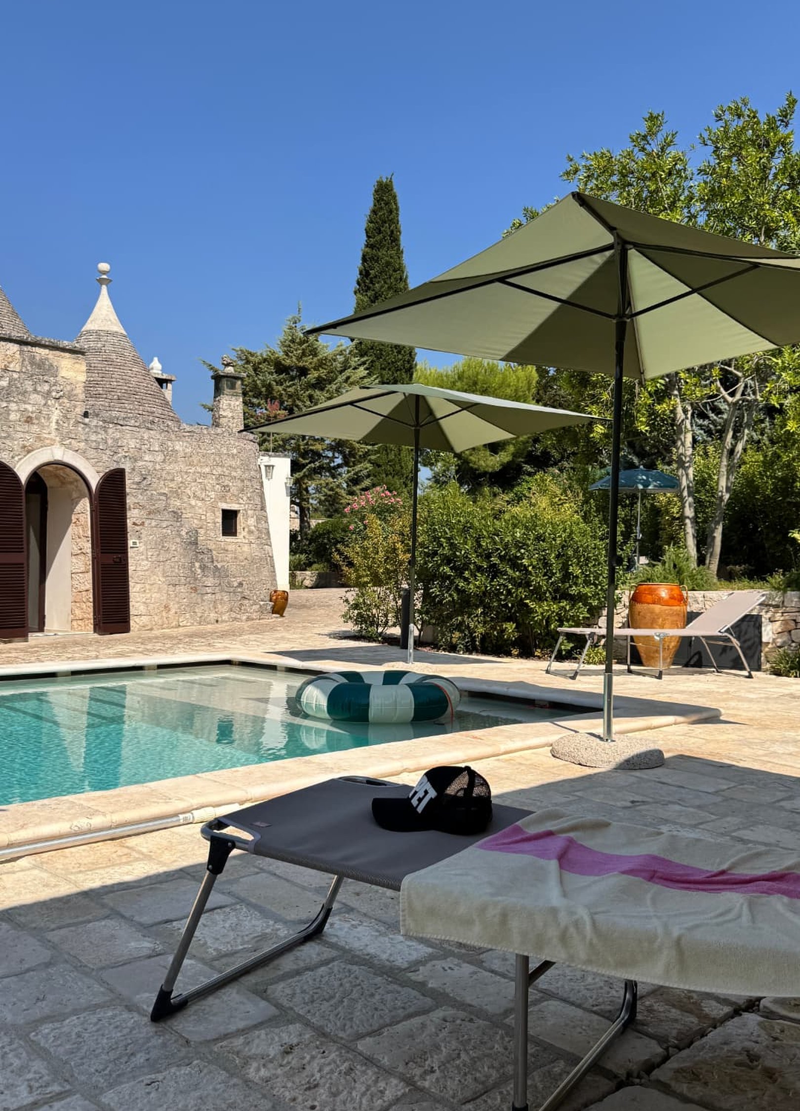 Trulli and the pool seen from a shaded stone terrace